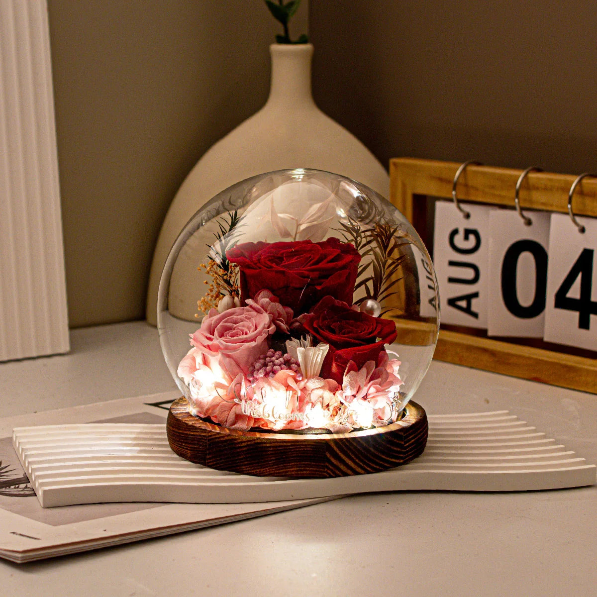 Queen of Hearts preserved red and pink roses in a lighted glass dome with a dark wood base, perfect for a romantic gift or bedside night light.